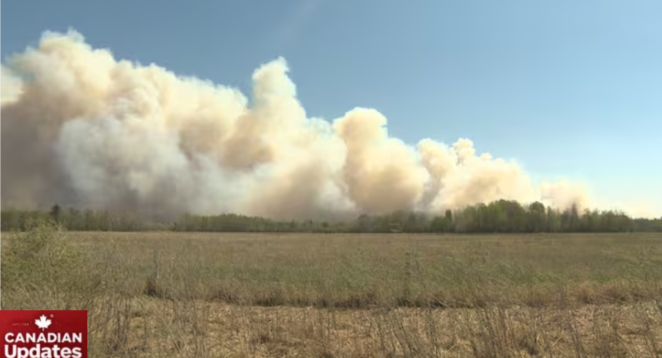 Wildfire burning near Lac du Bonnet, Manitoba, with smoke and flames visible in the distance.
